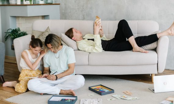 Father and daughter bonding in cozy living room with books and games, creating joyful family moments.