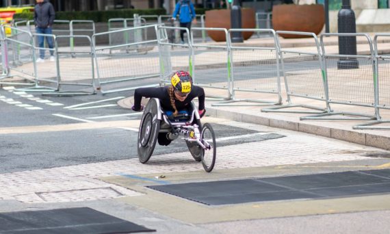 A dedicated athlete competes in a marathon using a racing wheelchair on city streets.
